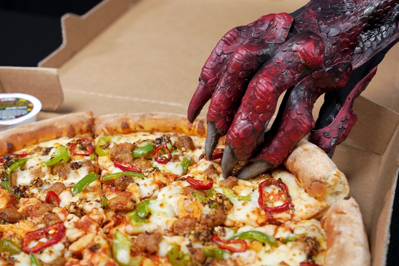 A dragon's claw grabbing a slice of pizza