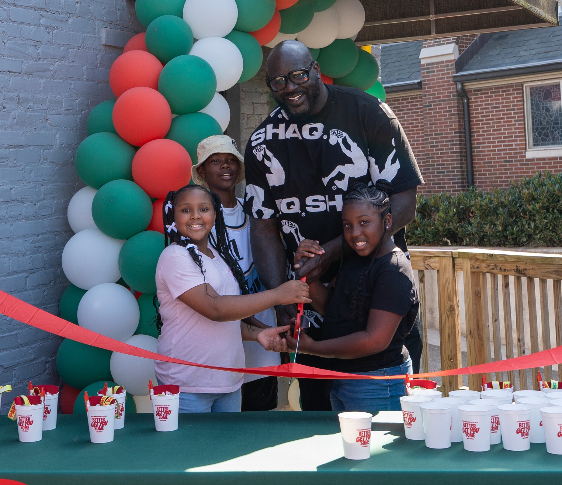 Shaq and children cutting the ribbon of new Papa Johns restaurant