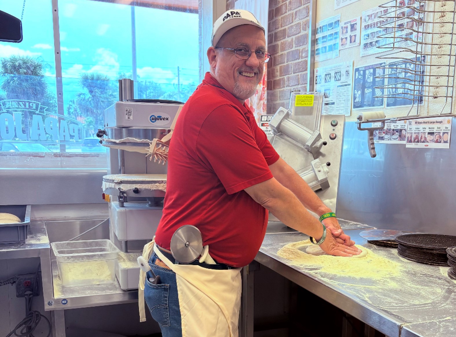 A man making a pizza inside a Papa Johns restaurant