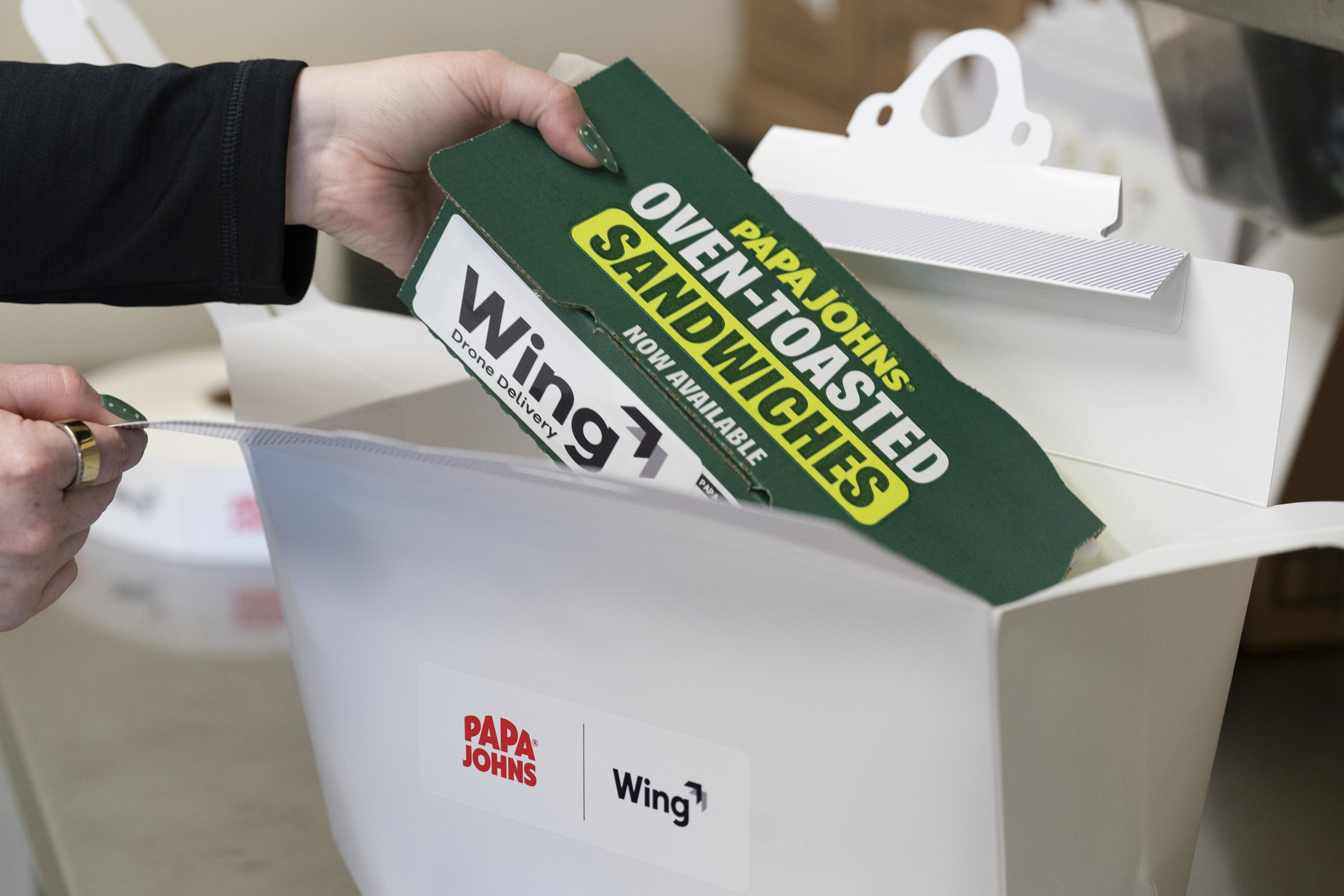 A Papa Johns sandwich being placed into a box for delivery via drone
