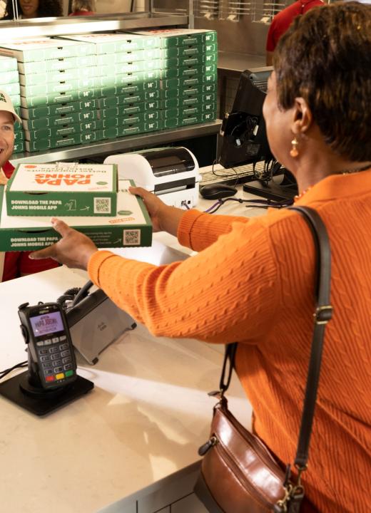 A Papa Johns team member handing order to a customer