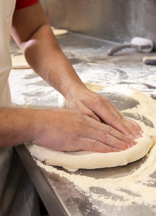 A person's hands preparing a pizza