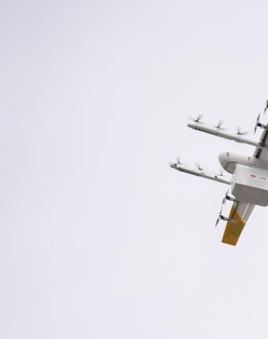 A drone carrying a Papa Johns order flying through the air