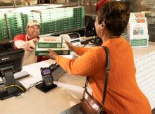 A Papa Johns team member handing order to a customer