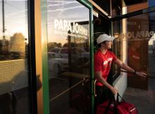 A delivery driver exits a Papa Johns restaurant