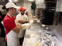 Papa Johns team members prepare pizza.