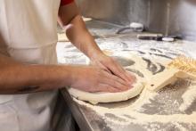 A person's hands preparing a pizza