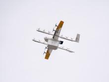 A drone carrying a Papa Johns order flying through the air