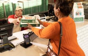 A Papa Johns team member handing order to a customer