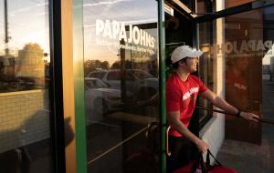 A delivery driver exits a Papa Johns restaurant