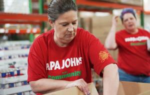 A Papa Johns volunteer packs meals at a food bank