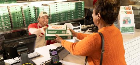 A Papa Johns team member handing order to a customer