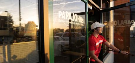 A delivery driver exits a Papa Johns restaurant