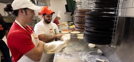 Papa Johns team members prepare pizza.