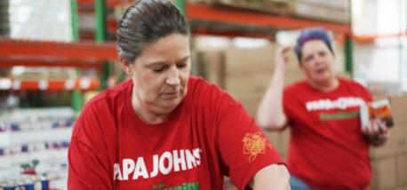 A Papa Johns volunteer packs meals at a food bank