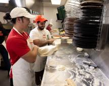 Papa Johns team members prepare pizza.